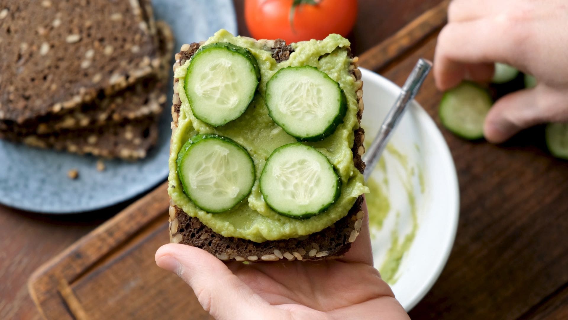 man preparing cucumber and avo on toast