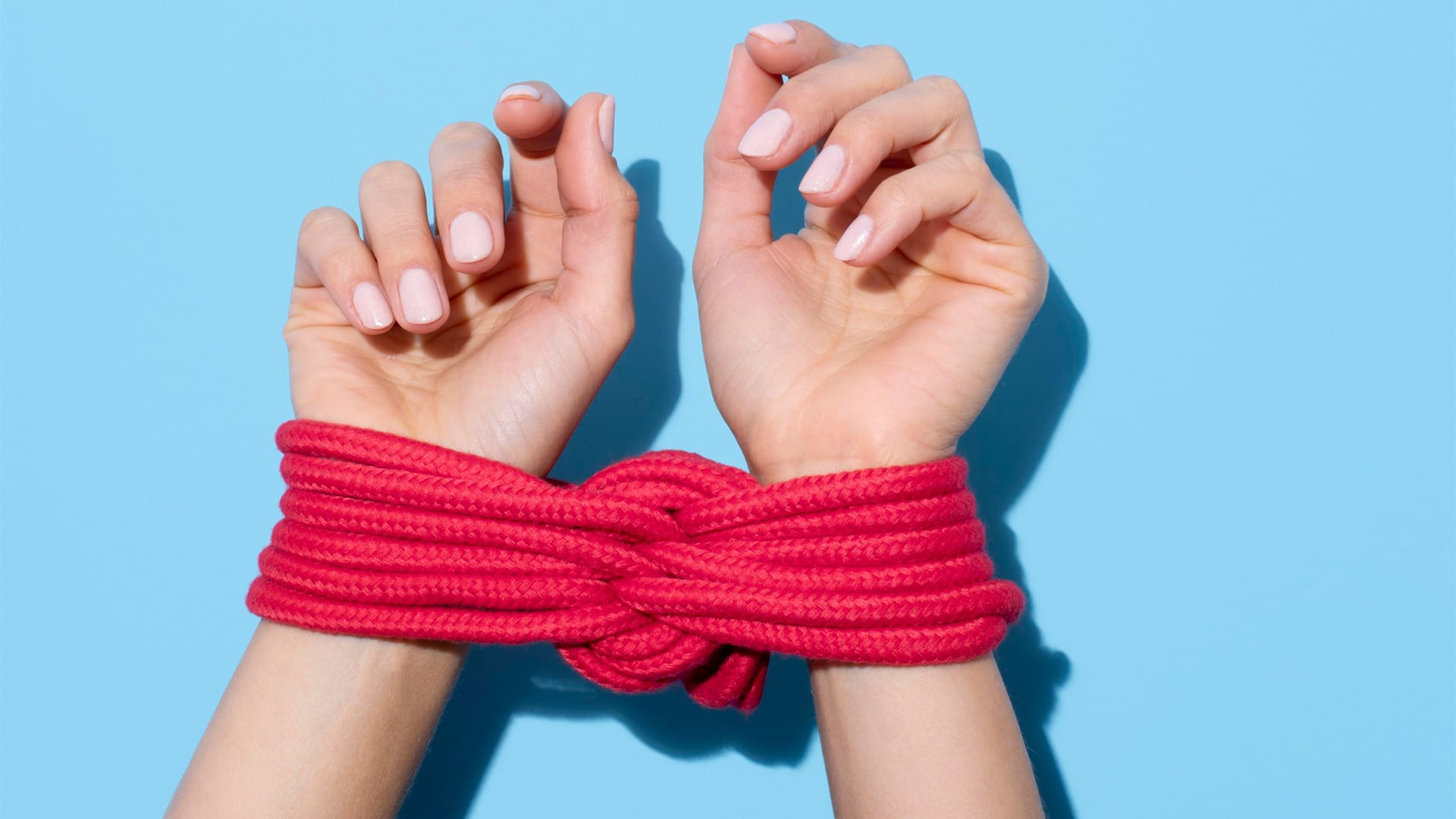 woman with her hands tied up with red rope on blue background learning how to role play