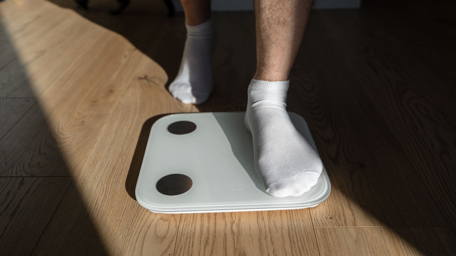 man in socks trying to lose weight stepping onto scale in the morning