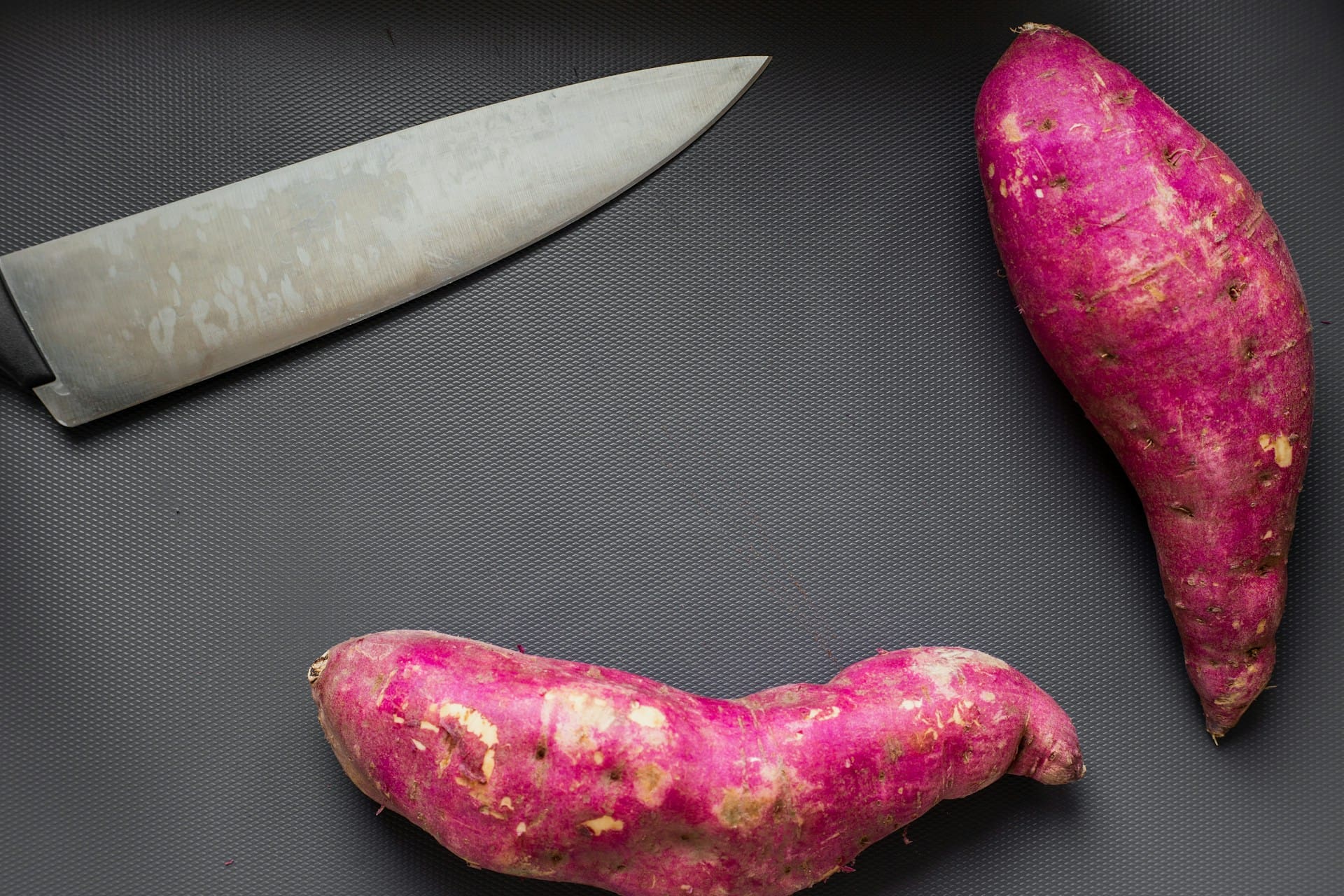 sweet potatoes on chopping board with sharp knife