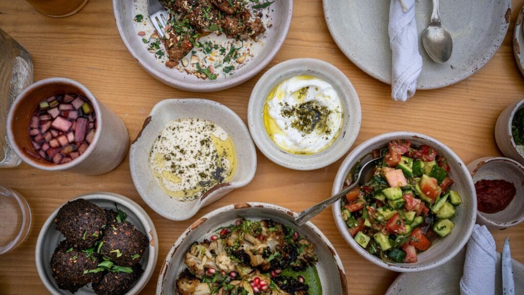 plates of Mediterranean dishes sitting on top of a wooden table